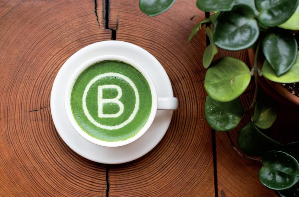 An overhead view of a matcha latte with the B-corp logo sprinkled in white on top